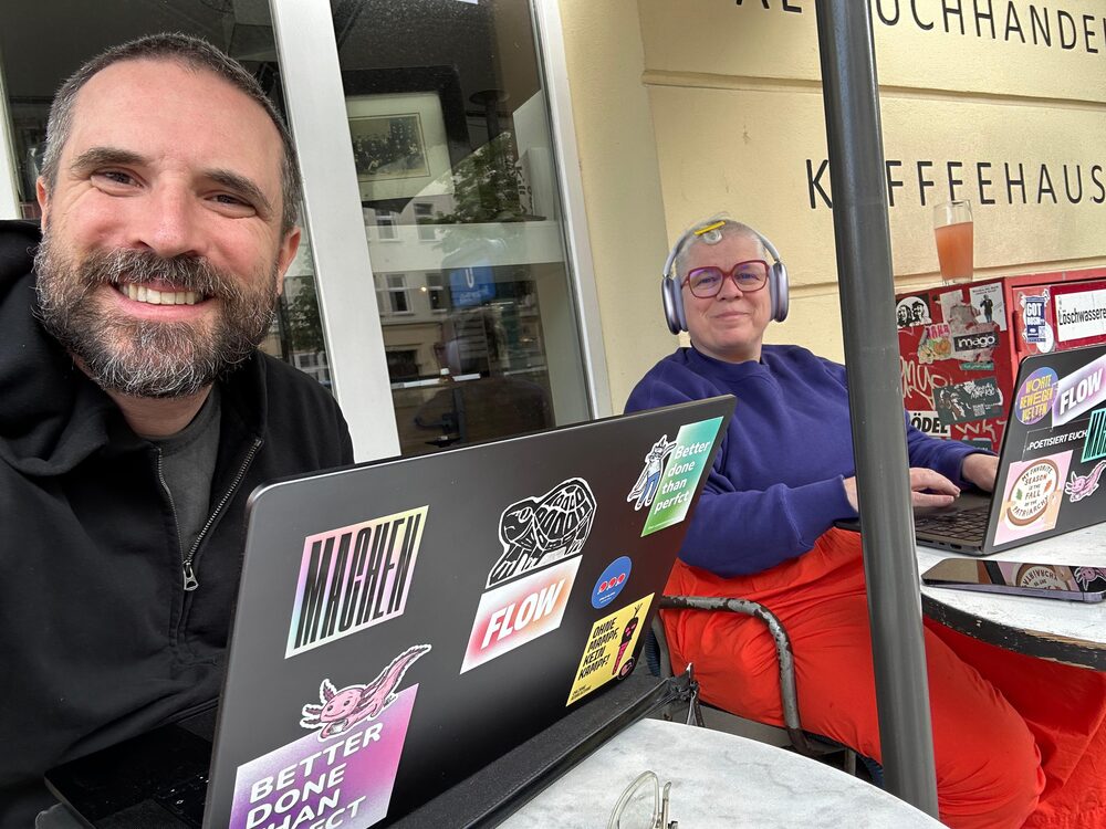 Nadja and a colleague working together on laptops outside a café
