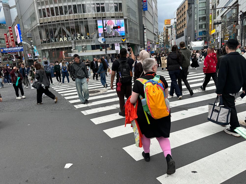 Nadja überquert die Shibuya-Kreuzung in Tokio mit einem orangen Rucksack